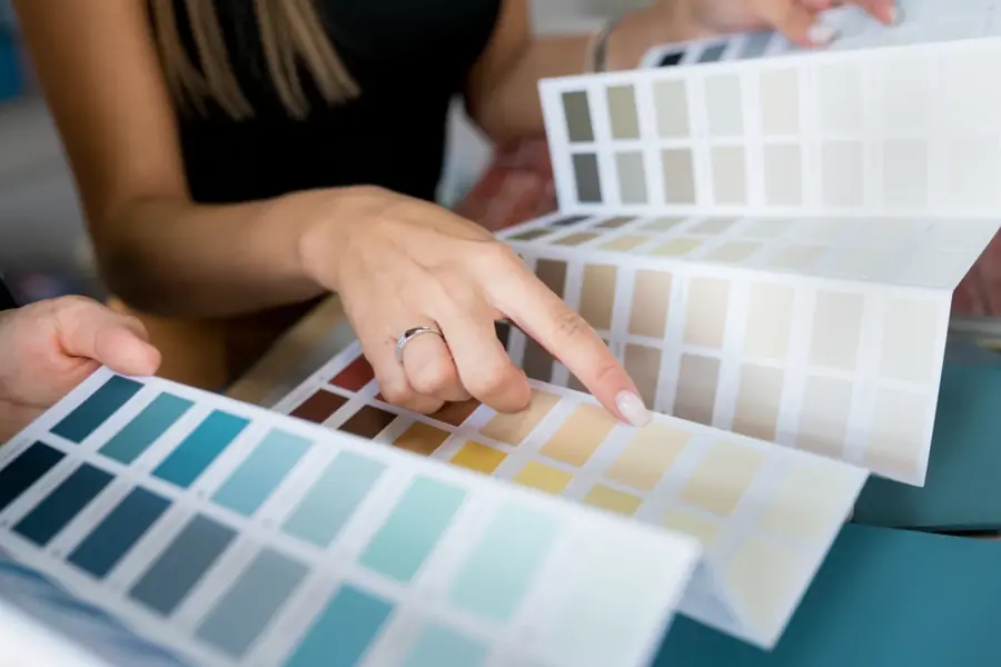 A woman pointing to a paint colour chip from a fanned set of colour cards